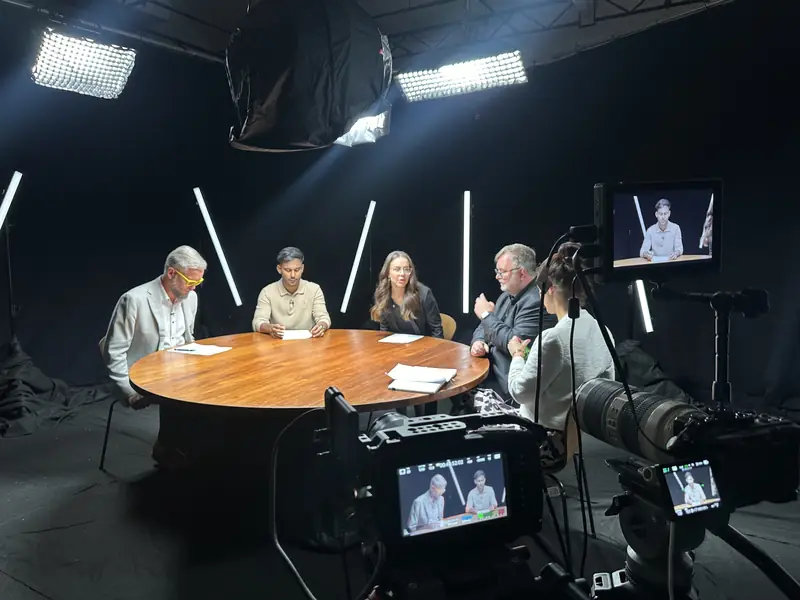 A studio panel recording with cameras and lights
